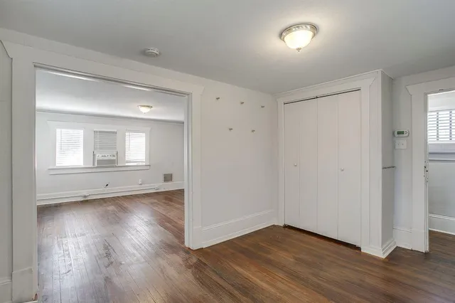 an empty room with wooden floor closet and windows