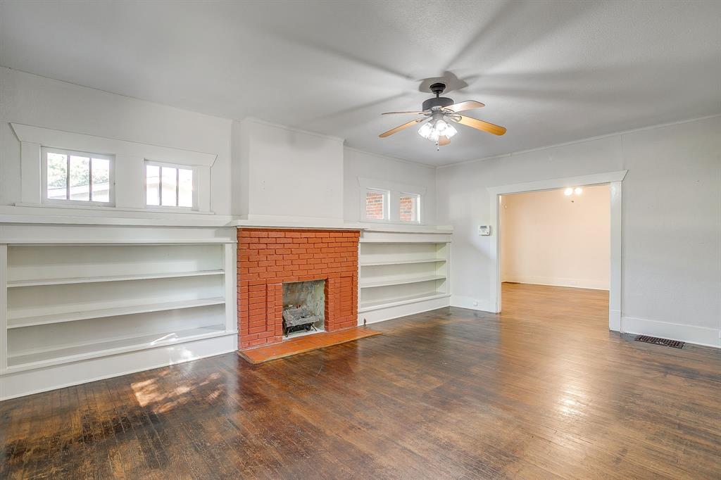 2312 Mistletoe Avenue Fort Worth, TX 76110 - Photo 9 of 40 a view of an empty room with wooden floor fireplace and a window