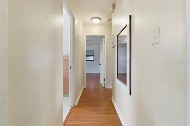 a view of a hallway with wooden floor and a bathroom