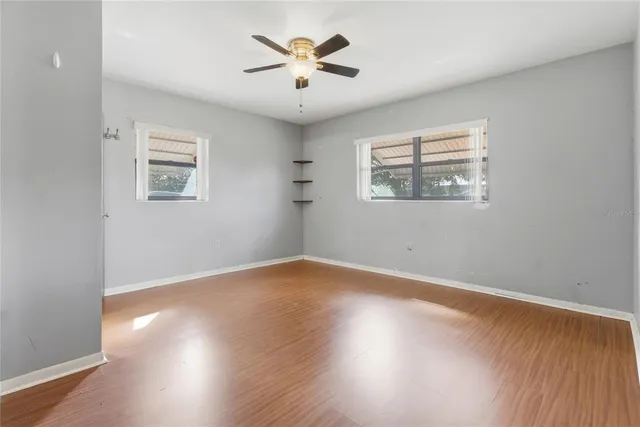 a view of empty room with wooden floor and fan