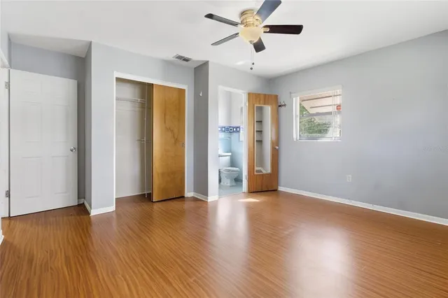 an empty room with wooden floor and windows