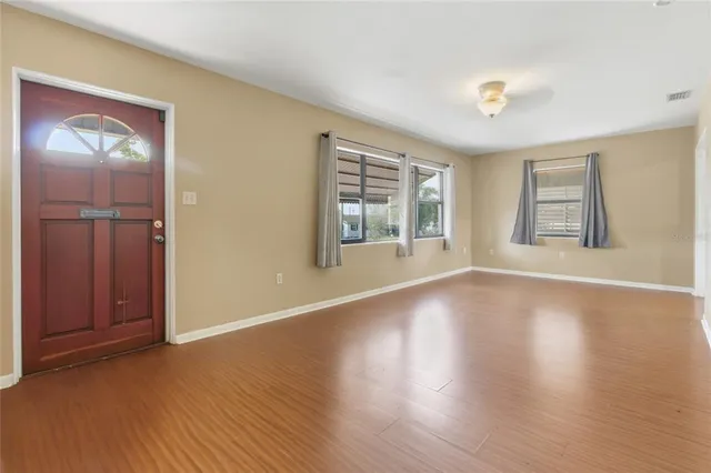 an empty room with wooden floor and windows