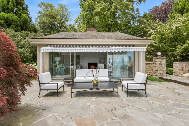 a view of a patio with a table and chairs under an umbrella with a large tree