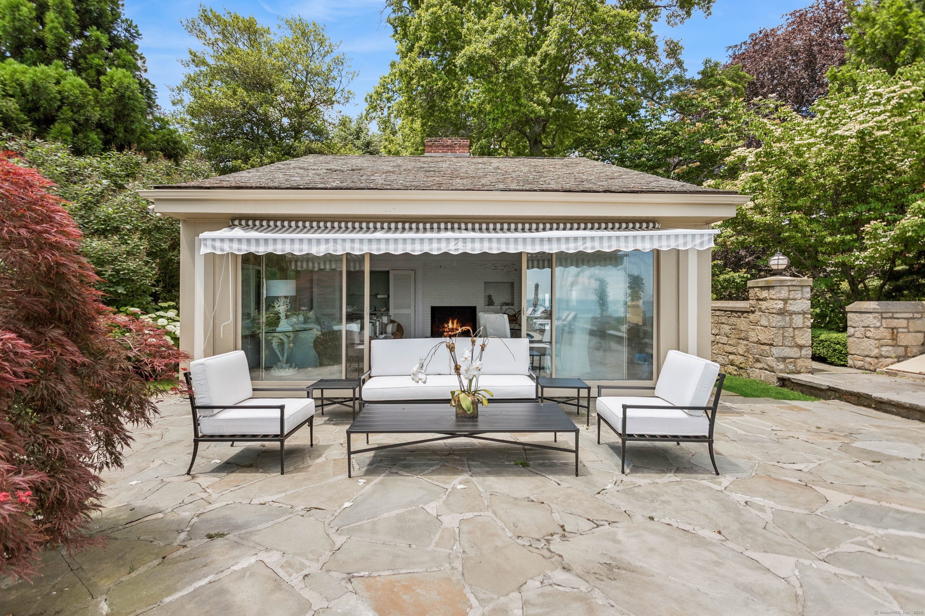 92 Beachside Avenue Westport, CT 06880 - Photo 22 of 28 a view of a patio with a table and chairs under an umbrella with a large tree