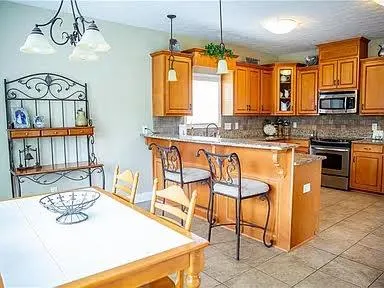 a kitchen with stainless steel appliances granite countertop a sink a stove a dining table and chairs