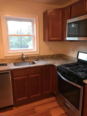 a kitchen with granite countertop a stove a microwave and window