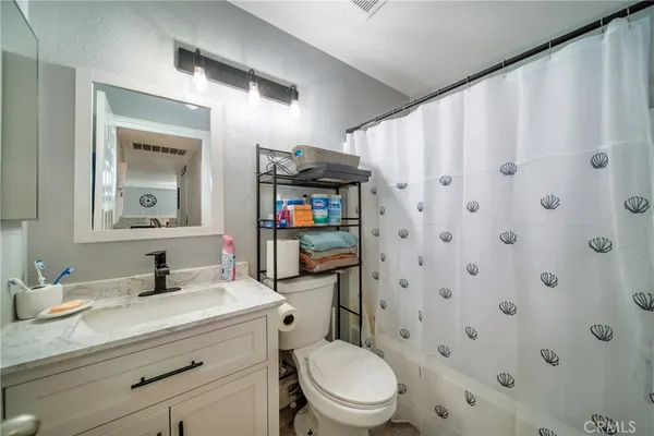 a bathroom with a granite countertop toilet sink and mirror