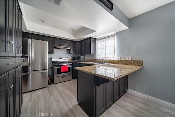 a kitchen with refrigerator and wooden floor