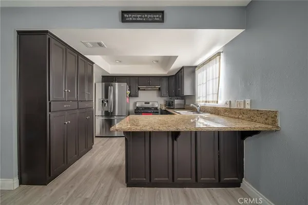 a kitchen with stainless steel appliances granite countertop a sink and wooden cabinets