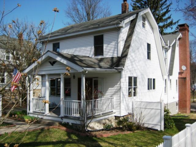 a view of a white house with a small yard and potted plants
