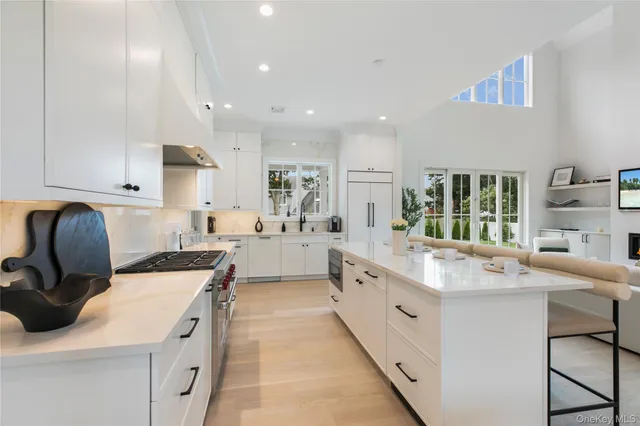 a large white kitchen with stainless steel appliances granite countertop a sink and a stove