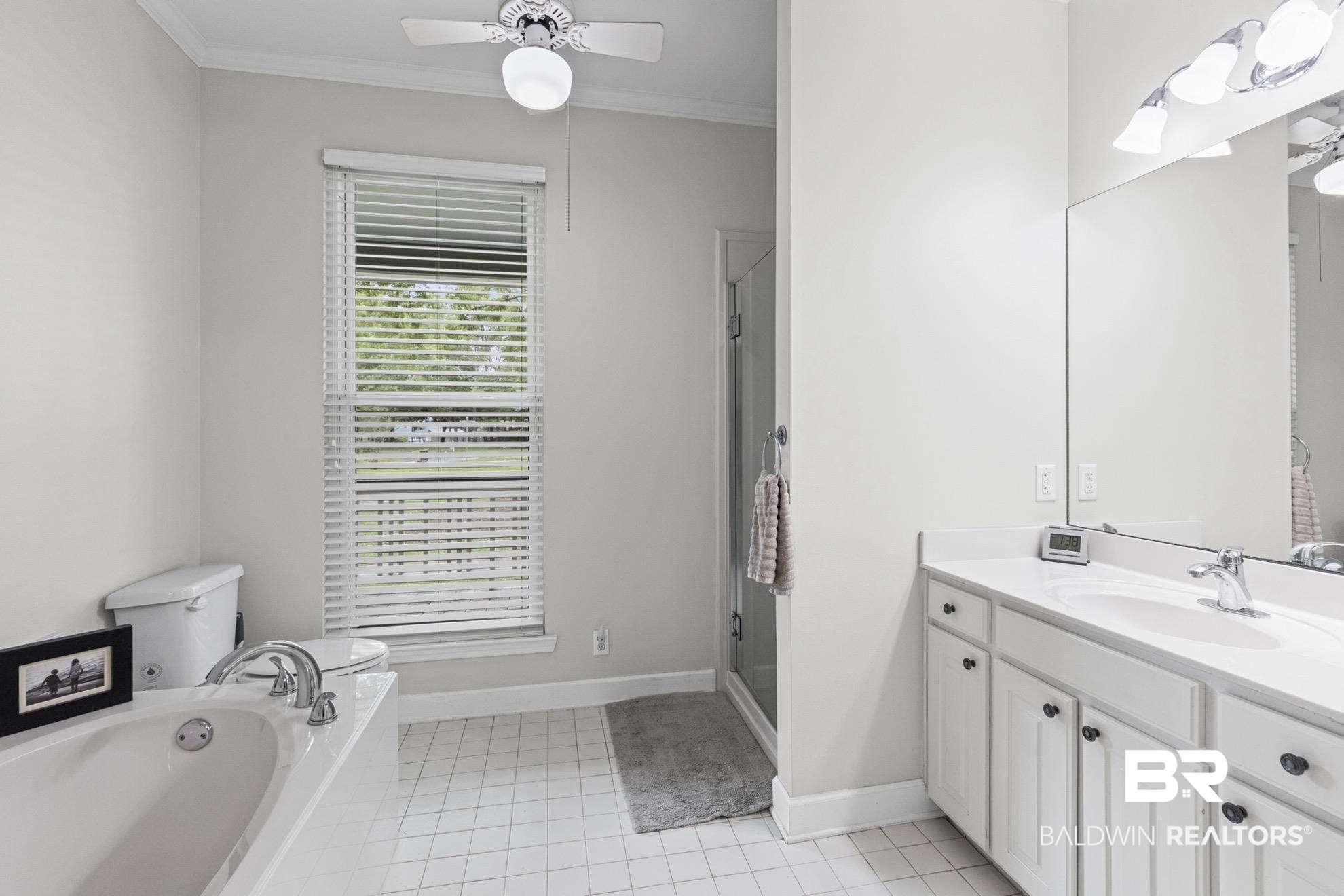 12171 Marguerite Drive Coden, AL 36523 - Photo 15 of 44 Bathroom featuring a soaking tub with polished chrome fixtures, white vanity with integrated sink, glass-enclosed shower, and a ceiling fan with light fixture