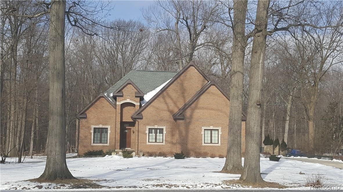 Front elevation with many mature trees.