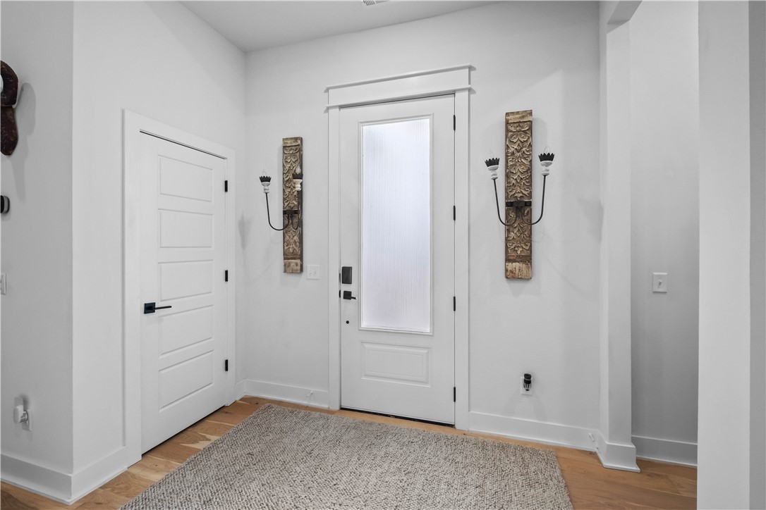 Entryway featuring light wood-finish flooring, white paneled doors with black hardware, and a modern front door with a frosted glass insert