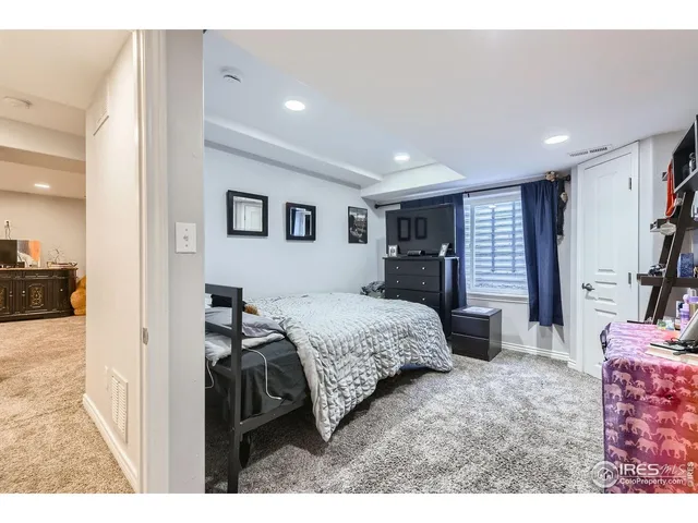 a bedroom with a bed a large window and dresser