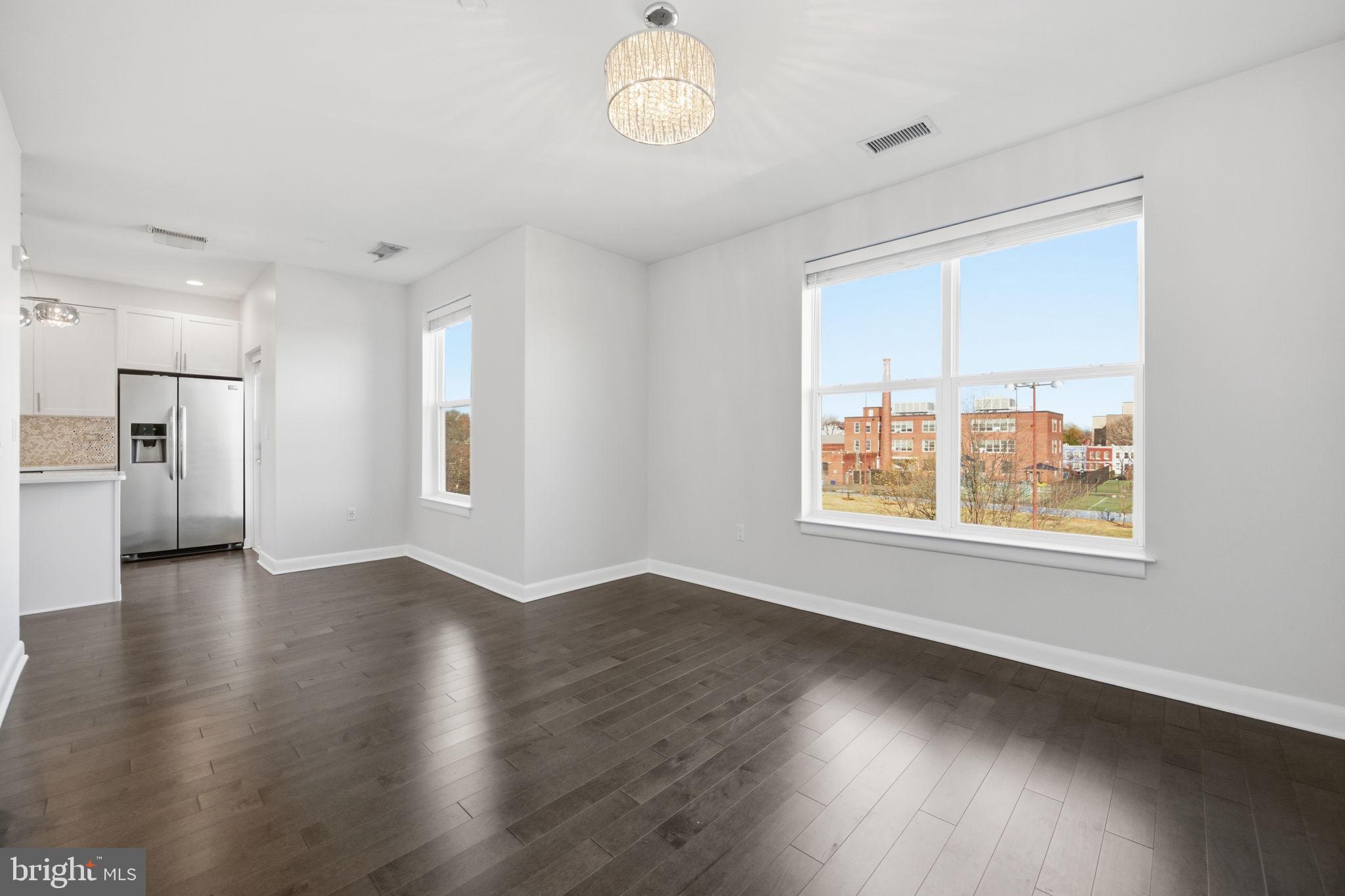 401 15th Street Southeast, Unit 401 Washington, DC 20003 - Photo 4 of 20 an empty room with wooden floor chandelier and windows