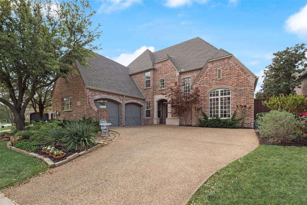 View of front facade with a shingled roof, driveway, and brick siding