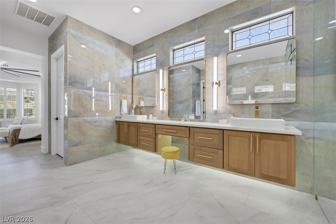 5015 Rivedro Street Las Vegas, NV 89135 - Photo 13 of 91 Marble tile flooring grounds a modern bathroom with dual vanities and contemporary fixtures.