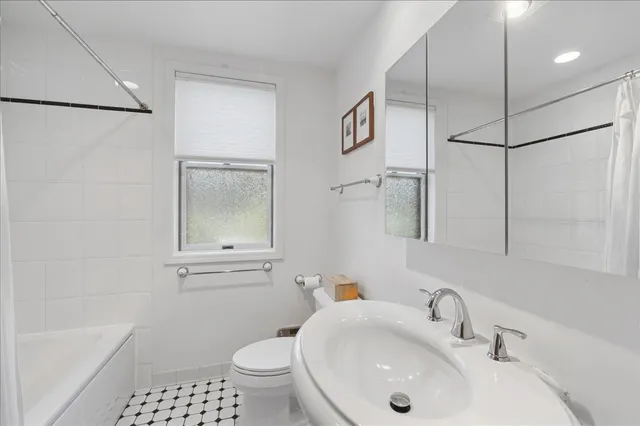 a bathroom with a sink a toilet a mirror and shower