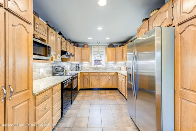a large kitchen with stainless steel appliances kitchen island granite countertop a refrigerator and a sink