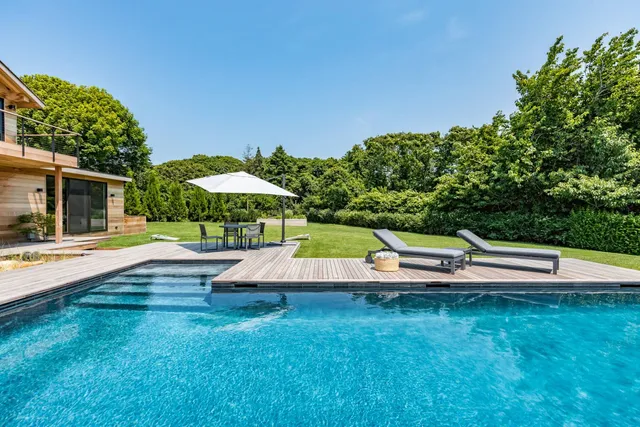 a view of pool with lawn chairs under an umbrella
