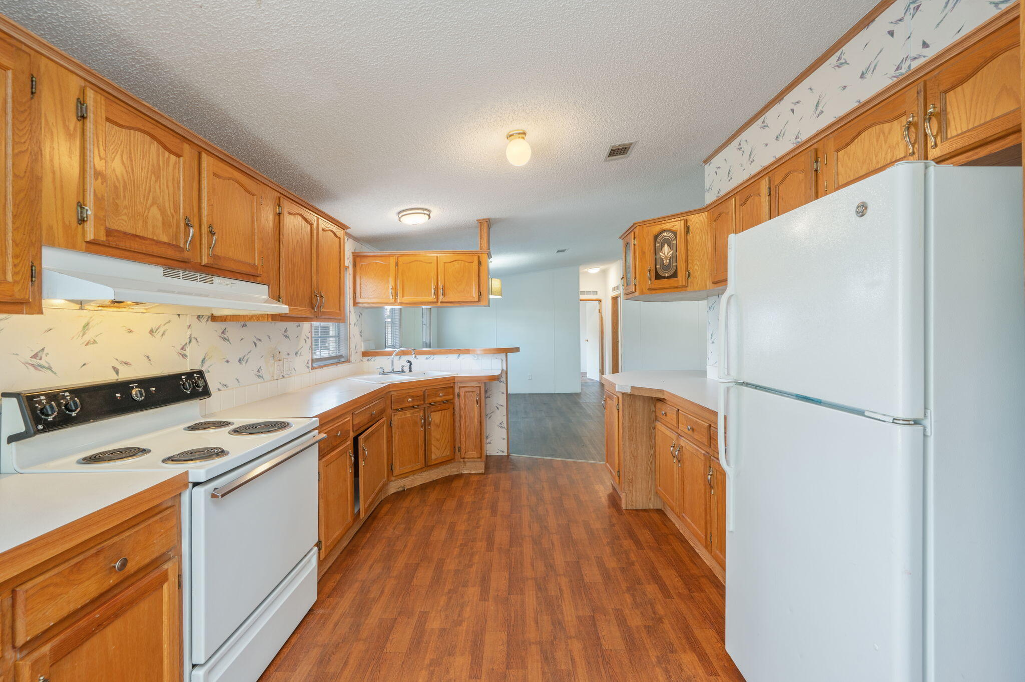 189 Benjamin Street Crestview, FL 32536 - Photo 16 of 40 a kitchen with a refrigerator a stove top oven a sink and cabinets with wooden floor