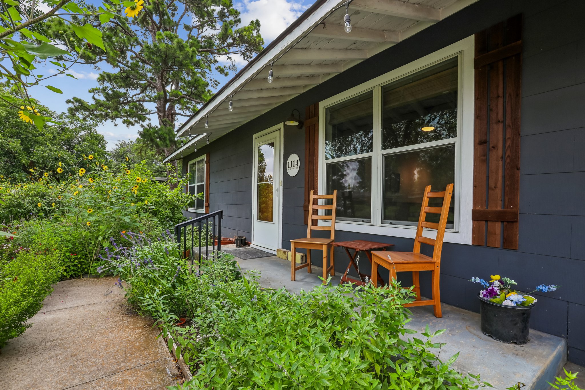 1114 West 2nd Street Elgin, TX 78621 - Photo 4 of 31 A charming entry with a front porch framed by flourishing garden beds, inviting serene outdoor moments.