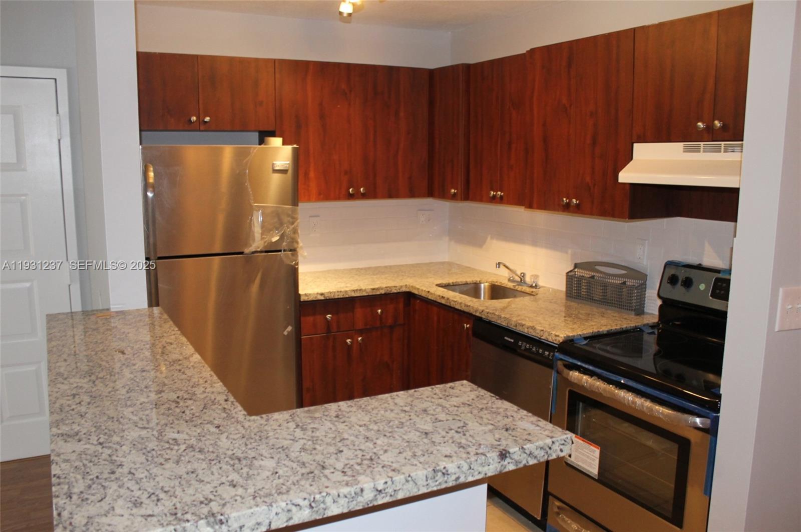 7135 Northwest 179th Street, Unit 302 Hialeah, FL 33015 - Photo 2 of 6 a kitchen with a refrigerator and a stove top oven