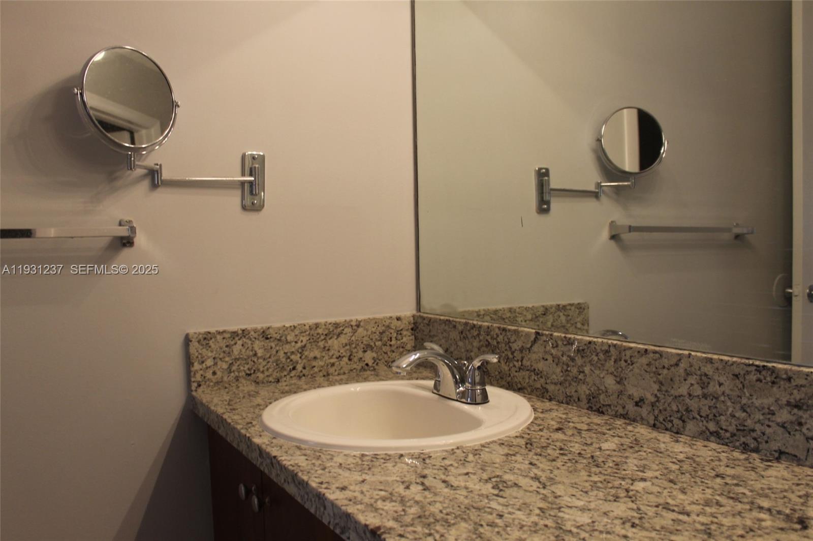 7135 Northwest 179th Street, Unit 302 Hialeah, FL 33015 - Photo 5 of 6 a bathroom with a granite countertop sink and a mirror