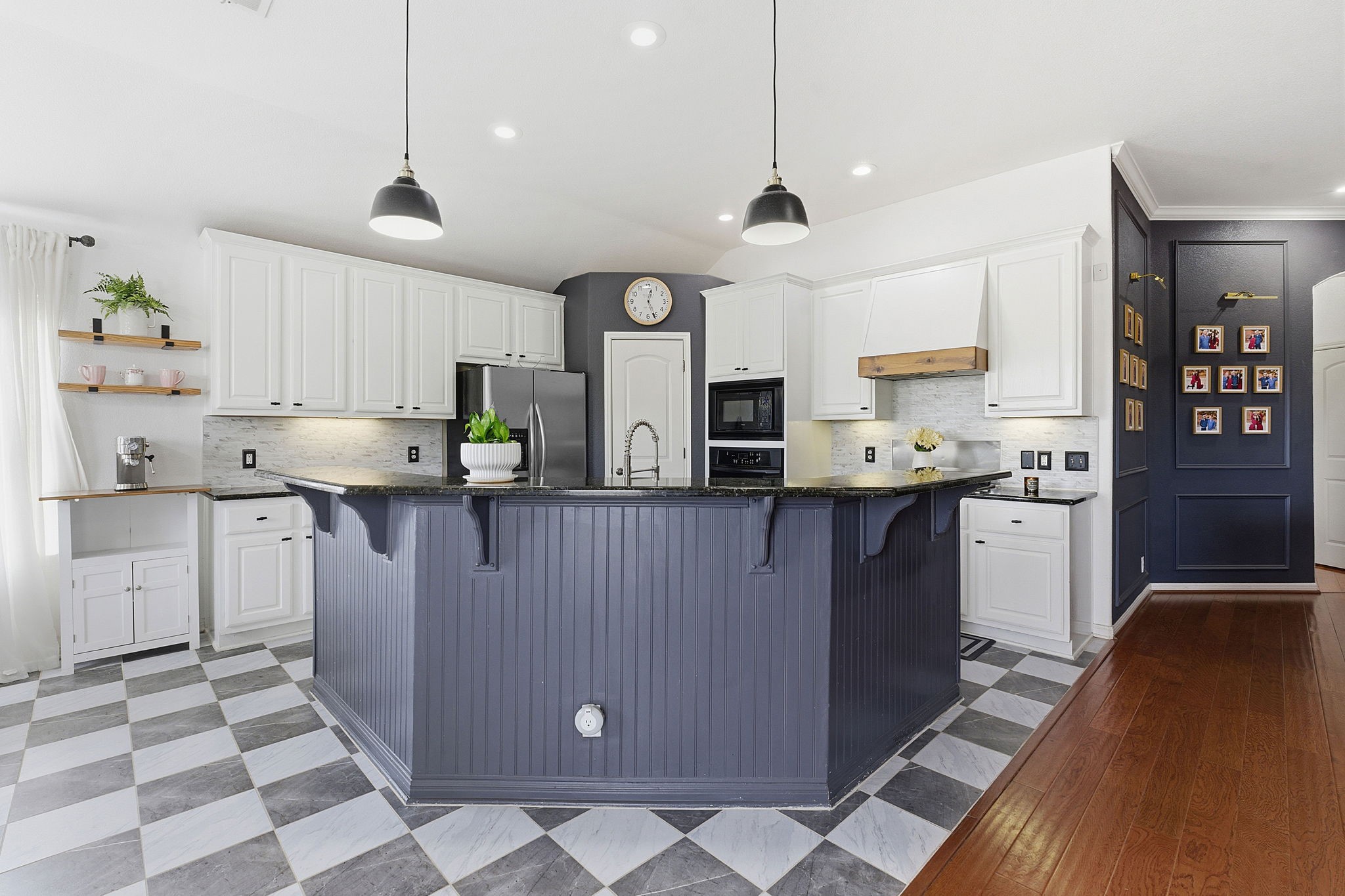 150 Manchester Lane Austin, TX 78737 - Photo 7 of 24 Kitchen with a breakfast bar, white cabinets, custom exhaust hood, black appliances, and a kitchen island with sink