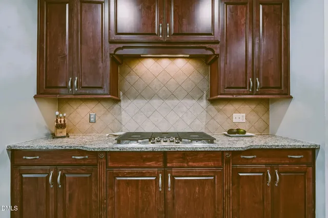 a view of kitchen with granite countertop wooden cabinets