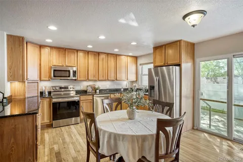 a kitchen with stainless steel appliances granite countertop a stove a refrigerator a microwave a sink and white cabinets with wooden floor