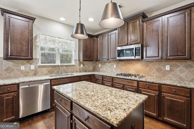 a kitchen with stainless steel appliances granite countertop wooden cabinets a stove a sink and a microwave