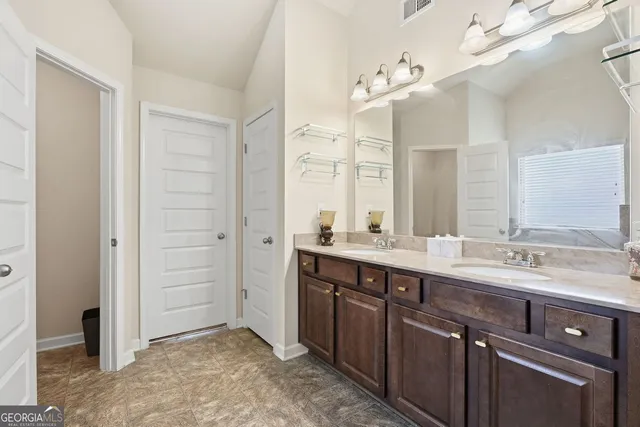 a spacious bathroom with a double vanity sink a large mirror and a shower