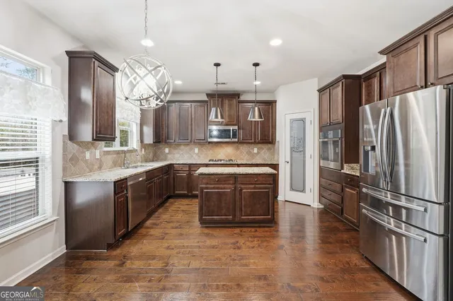 a large kitchen with granite countertop a refrigerator oven a sink dishwasher a dining table and chairs