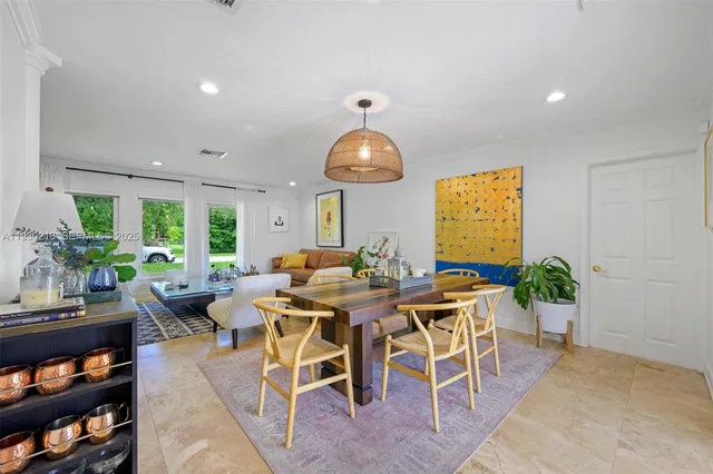 a view of a dining room and livingroom with furniture wooden floor a rug a potted plant and a chandelier