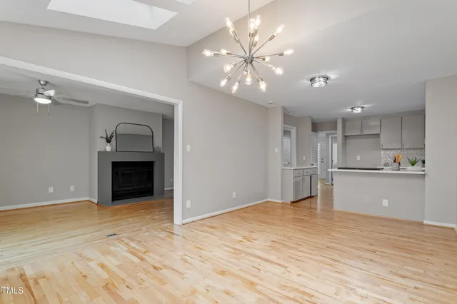 a view of an empty room with kitchen and a window