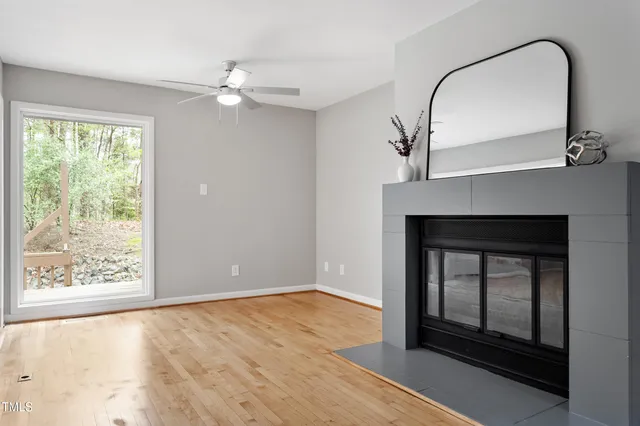 a view of an empty room with wooden floor fireplace and a window