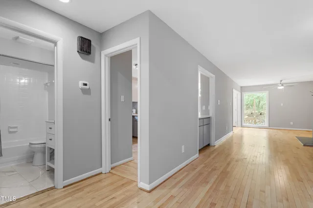 a view of an empty room with wooden floor and a bathroom