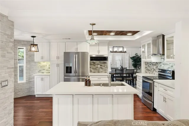 a kitchen with stainless steel appliances a refrigerator a stove a sink a oven and white cabinets with wooden floor