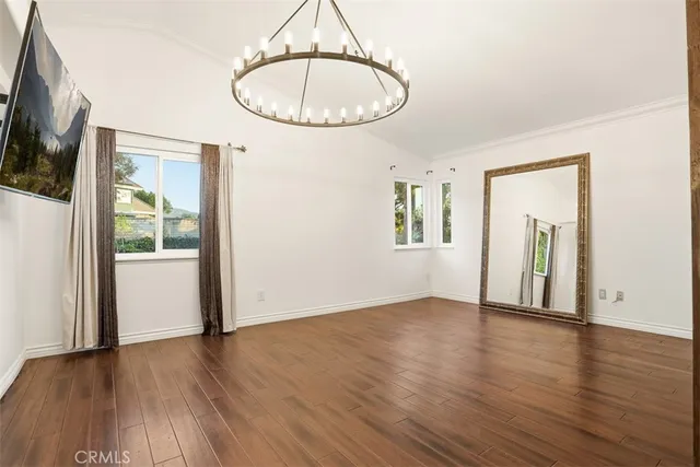 an empty room with wooden floor mirror and windows