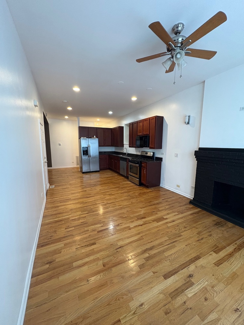 524 West 78th Street, Unit 1 Chicago, IL 60620 - Photo 3 of 9 a large room with wooden floor and a ceiling fan