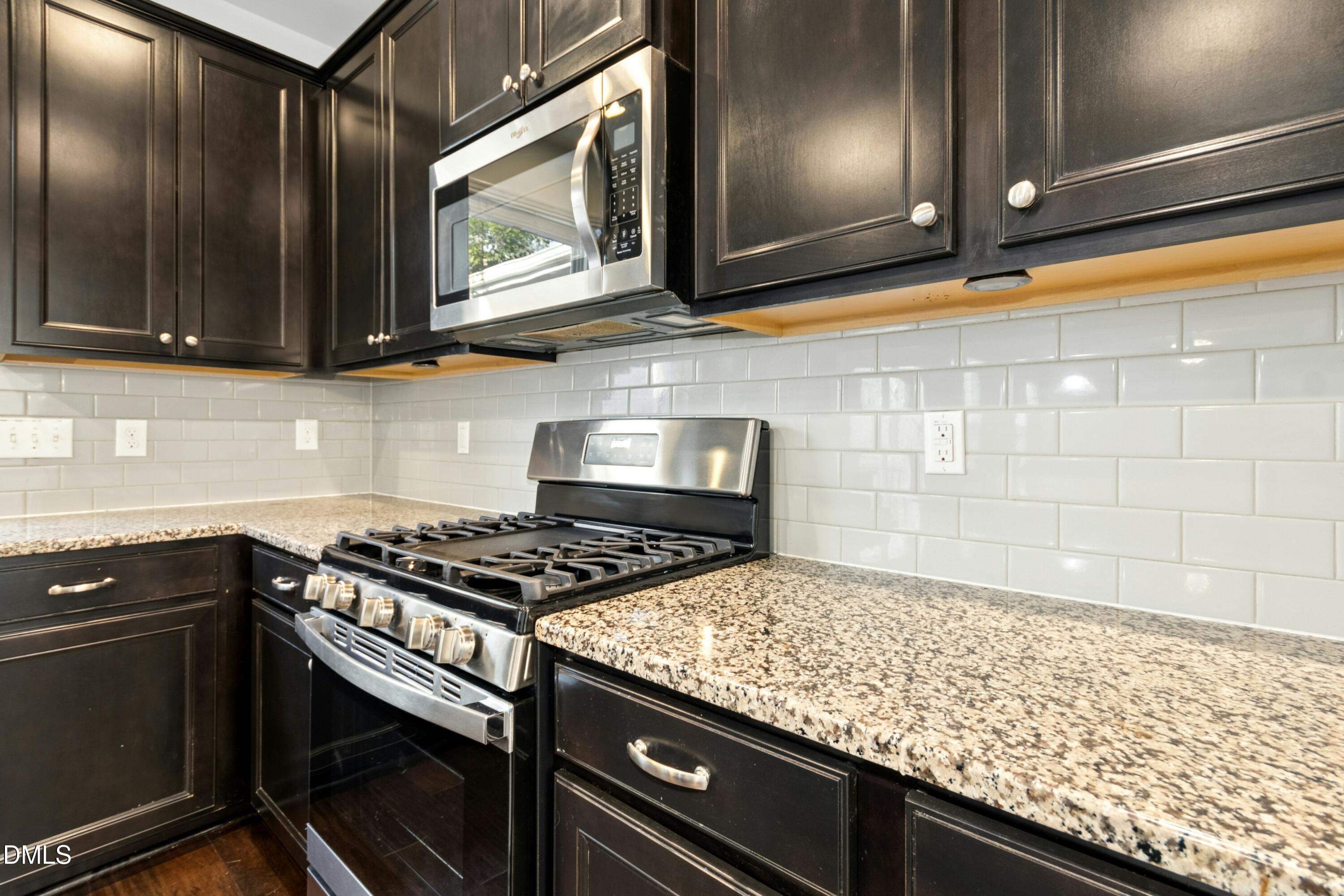 125 Spring Pine Lane Holly Springs, NC 27540 - Photo 10 of 34 a kitchen with stainless steel appliances granite countertop a stove a sink and a microwave