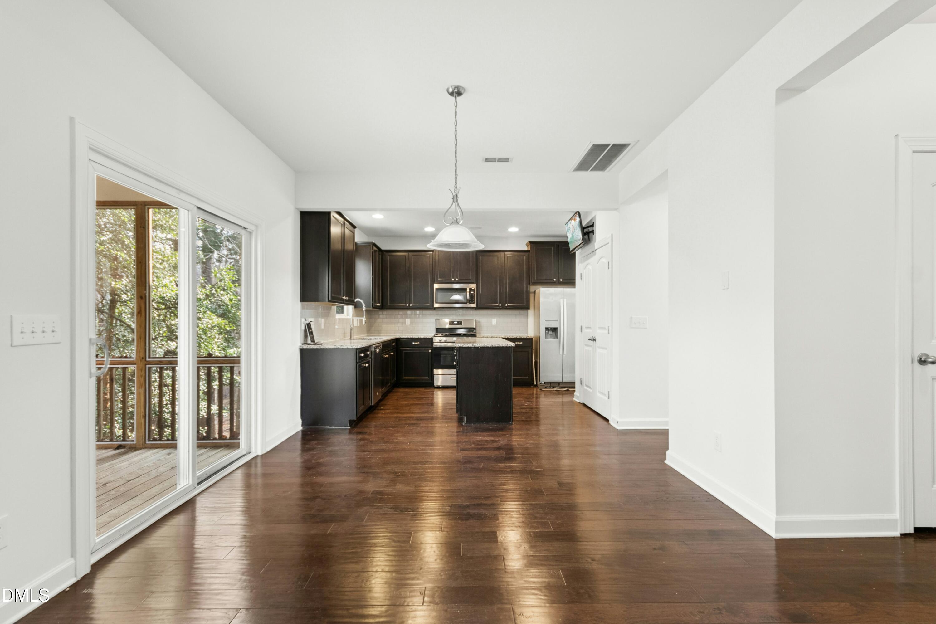 125 Spring Pine Lane Holly Springs, NC 27540 - Photo 12 of 34 a kitchen with stainless steel appliances kitchen island granite countertop a refrigerator a oven a stove and a wooden floors