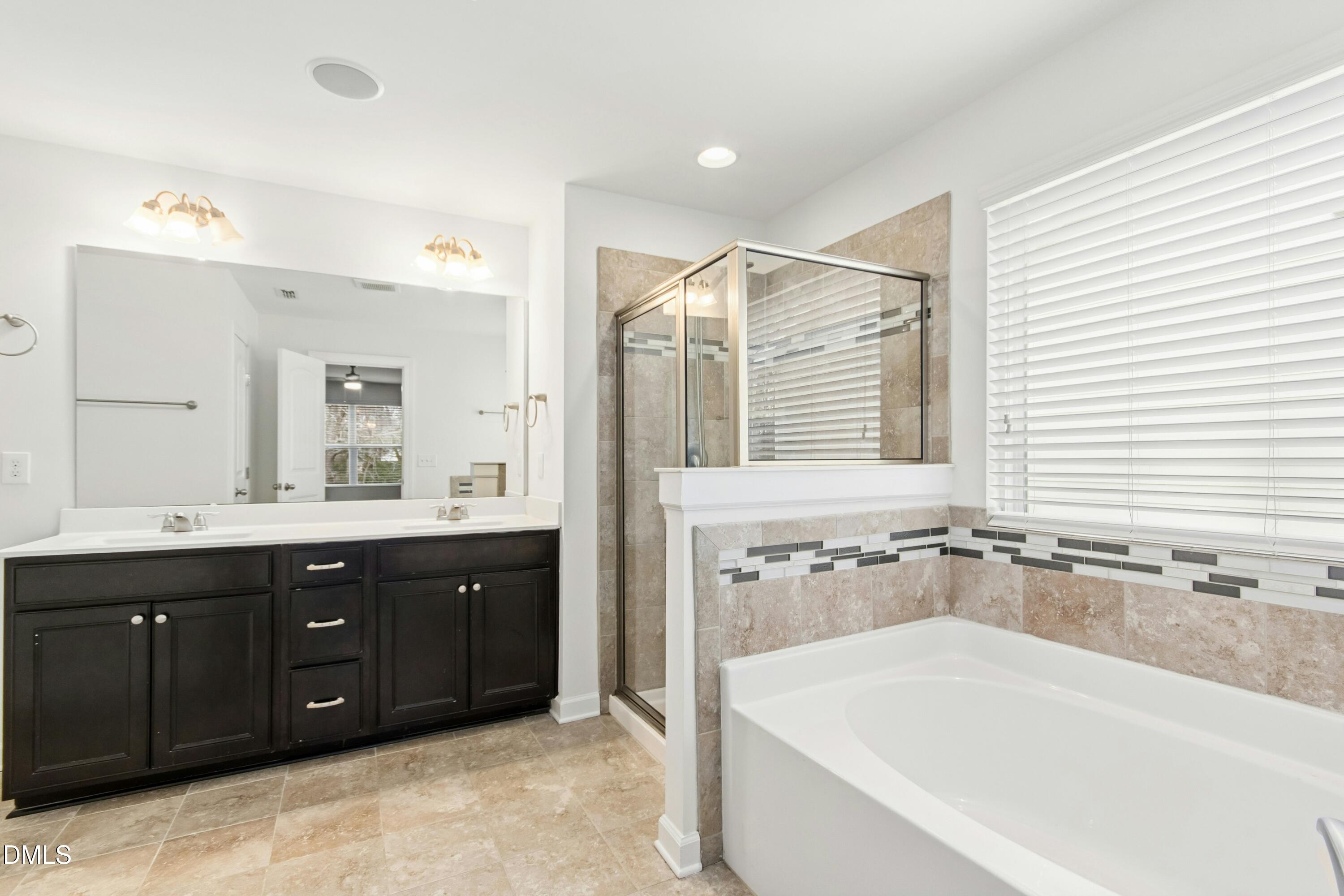 125 Spring Pine Lane Holly Springs, NC 27540 - Photo 19 of 34 a bathroom with a bathtub sink double vanity and mirror