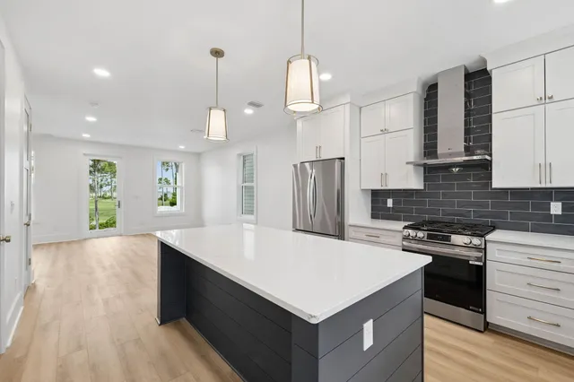 a view of kitchen with kitchen island a sink wooden floor and a refrigerator