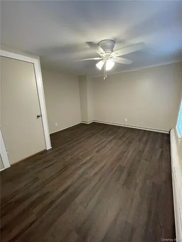 an empty room with wooden floor fan and window