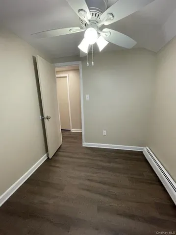 an empty room with wooden floor and fan