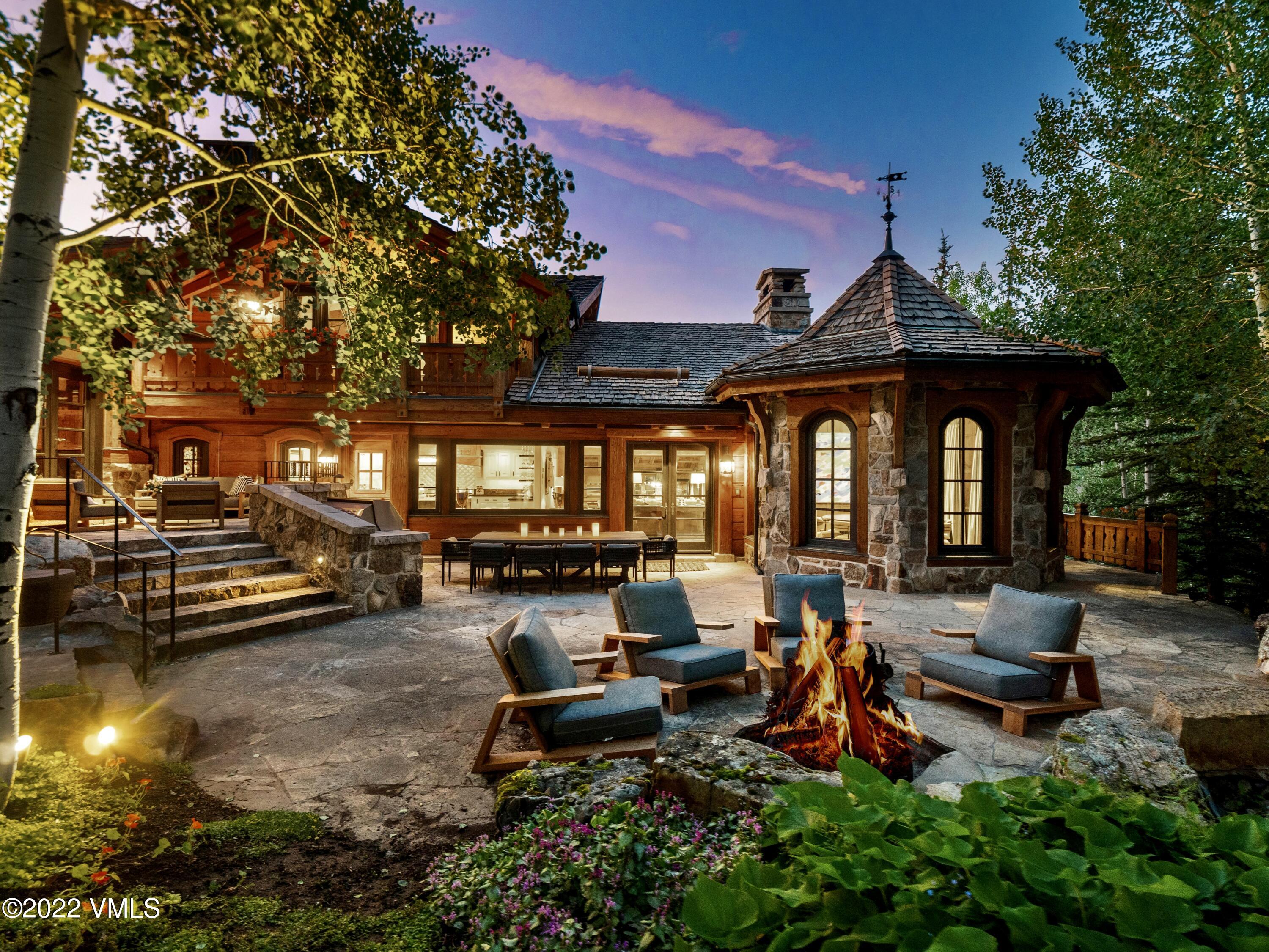 97 Rockledge Road Vail, CO 81657 - Photo 4 of 35 a view of a swimming pool with lawn chairs and a dining table and chairs under an umbrella