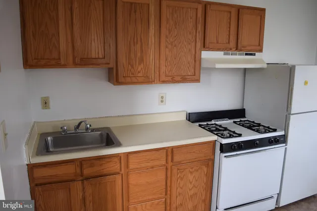 a kitchen with granite countertop wood cabinets and white appliances